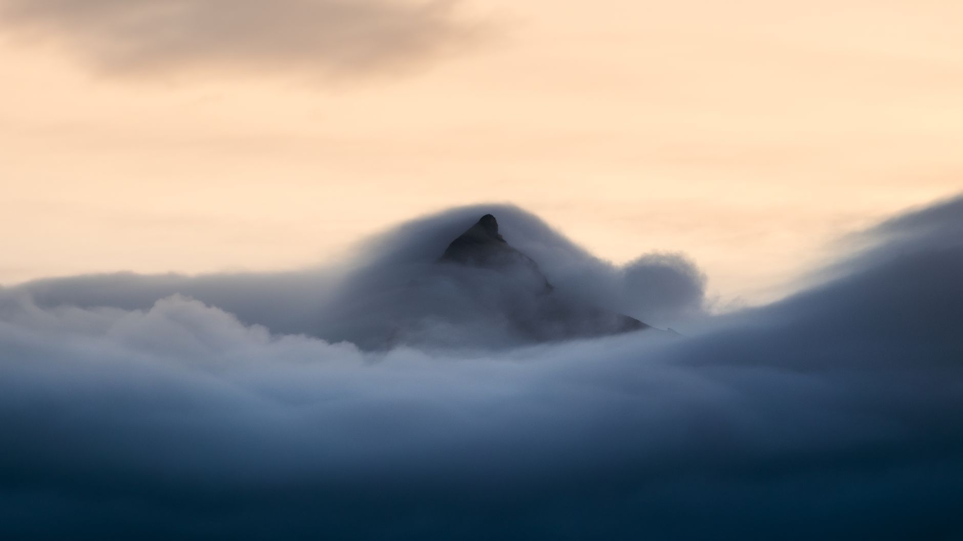 dramatic mountain peak emerge from cloud blanket